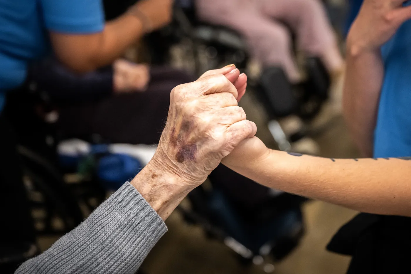 Caregiver gently holding a resident's hand