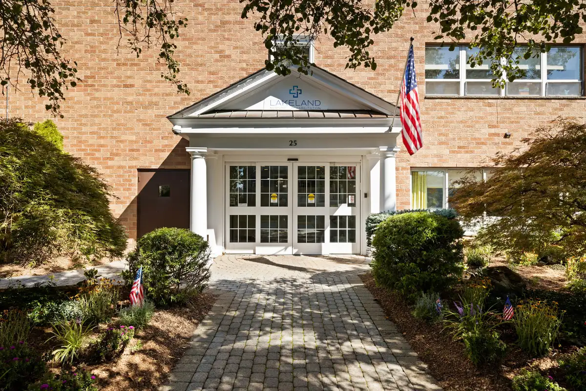 Front entrance of Amara Rehab and Nursing with white portico and American flag